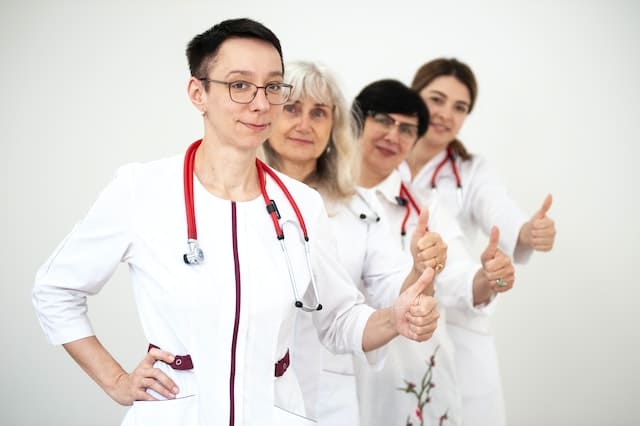 Четыре женщины медика показывают жест лайк