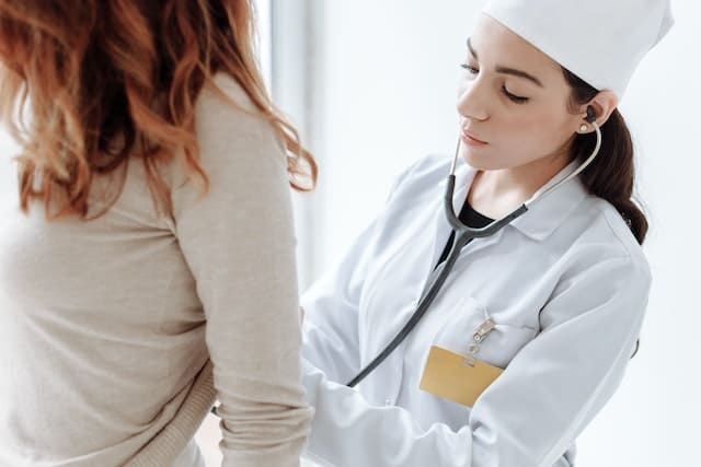 Девушка врач осматривает пациентку со стетоскопом