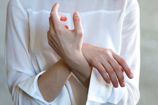Скрещенные руки усталой или больной девушки в белом одеянии