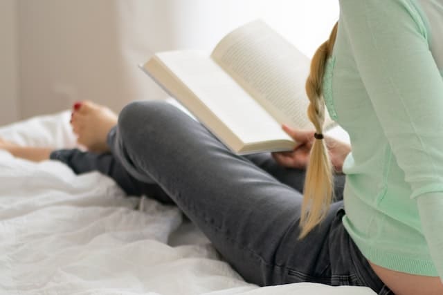 Девушка полулежа читает книгу