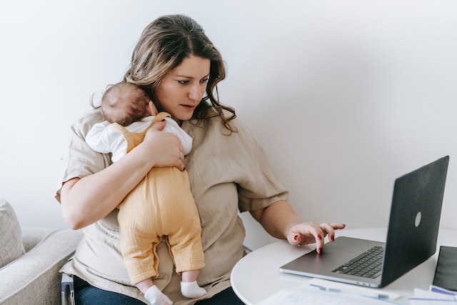 Женщина с грудным ребенком работает с ноутбуком